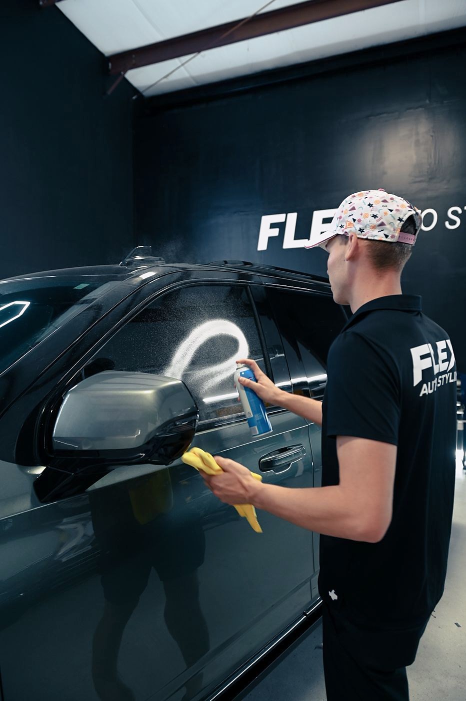 A FLEX installer polishing a dark car in the shop